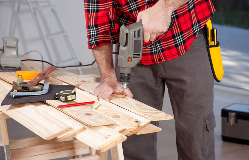 woodworker using a hand helo drill