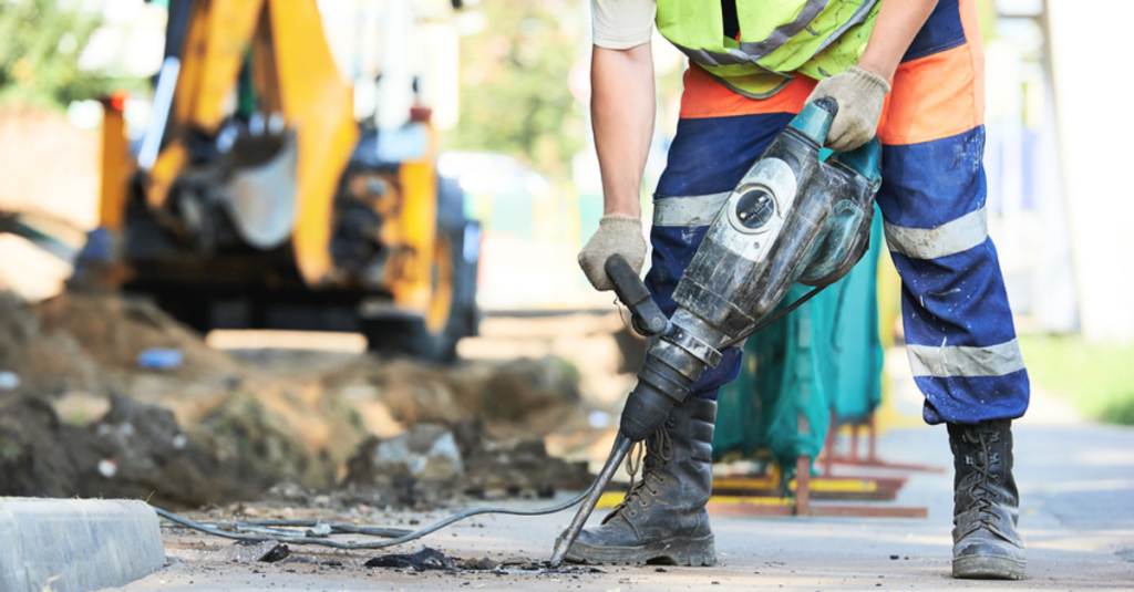 Construction worker using a drill with PPE for Hand Arm Vibrations